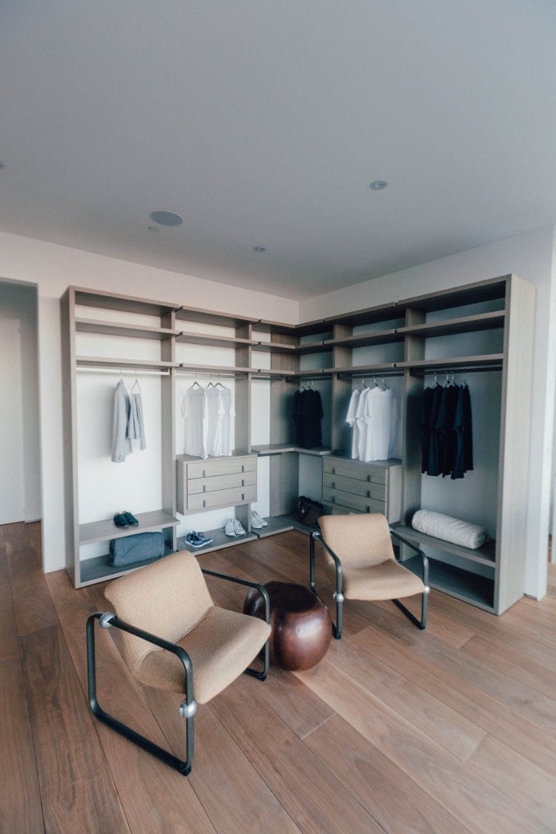 Spacious mens closet with two beige chairs